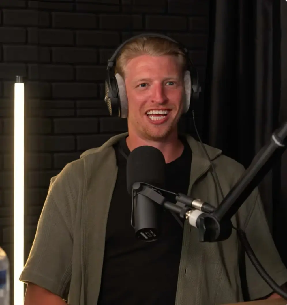 A smiling host of The SPEAK Podcast at the microphone in the studio