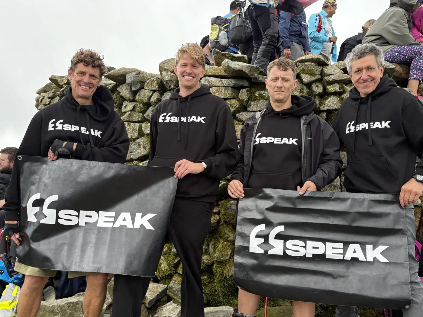 Four SPEAK members at a mountain summit holding SPEAK banners